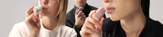 Two women and a man posing together, each holding a refillable lip balm near their lips to showcase a shared, sustainable skincare routine.