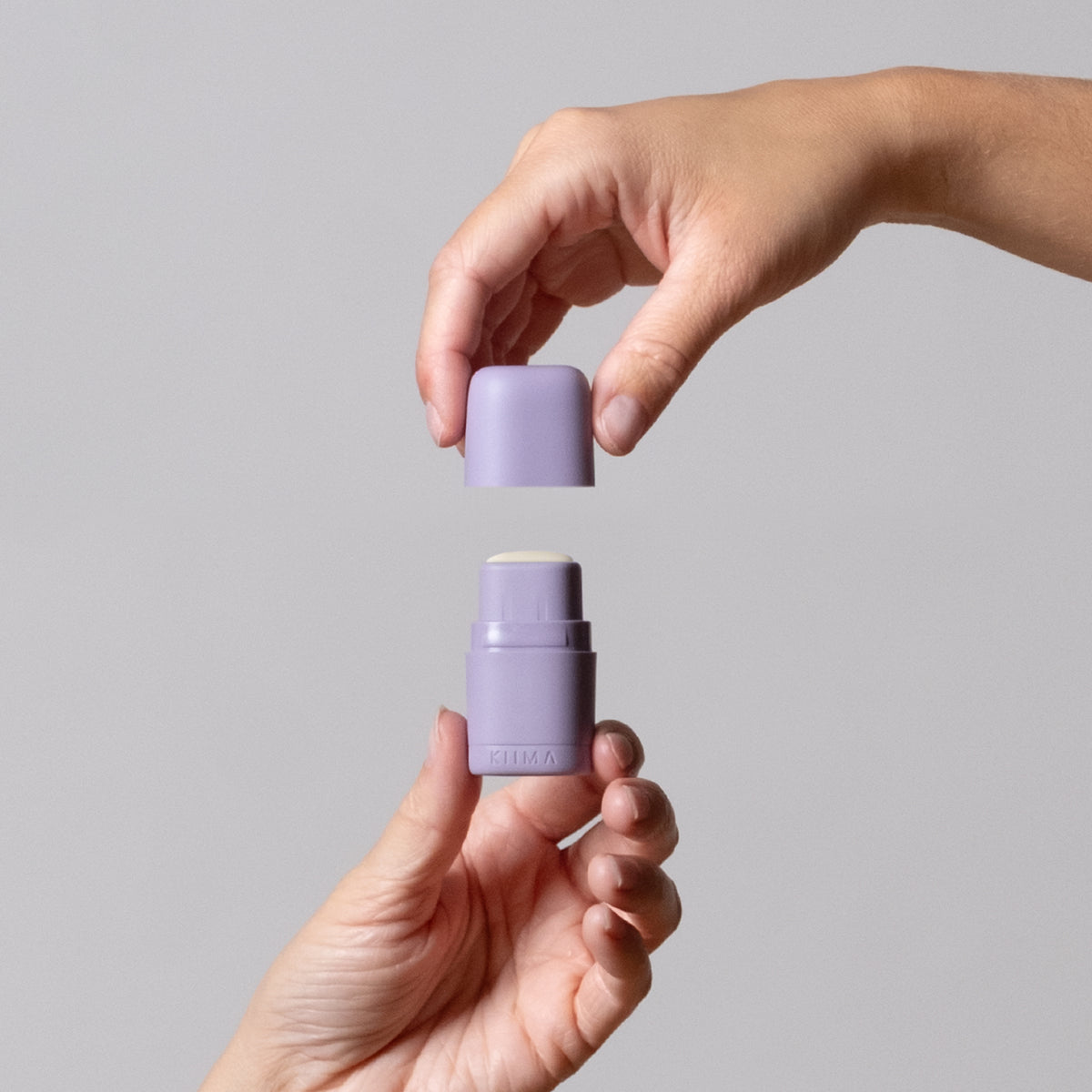 2 handsclosing a KIIMA refillable purple applicator, with a natural lip balm inside, eco-friendly packaging