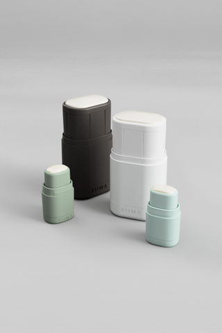 Minimalist KIIMA refillable deodorant case in sage green on a stone surface with a lavender sprig and organic skincare ingredients.